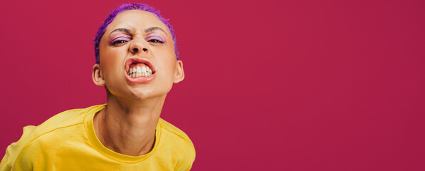 Quirky young woman making a face in a studio - obrazy, fototapety, plakaty