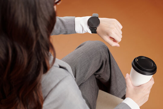 Businesswoman enjoying coffee break and reading notifications on smartwatch