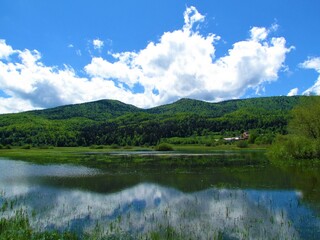 Scenic view of lake Cerknica and Javorniki hills in Notranjska, Slovenia with a reflection of the hills and the clouds in the lake