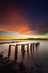 Fototapeta premium Abandoned pillars in a beautiful scenery of the sunset at the beach