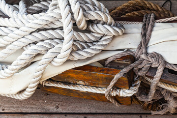 Old pulley ropes and sail on the wooden deck of an old ship.