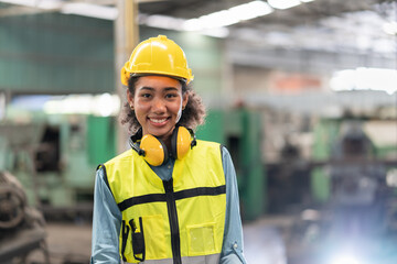 Portrait of female engineer in safety vest with yellow helmet smiling stand to work at factory...