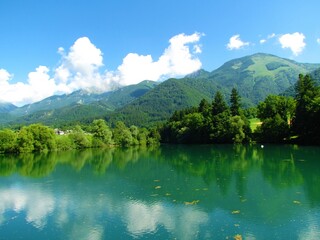 Beautiful lake Crnava near Preddvor in Upper Carniola, Slovenia and mountains Srednji Vrh and Storzic in Kamnik-Savinja alps behind with a reflection of the trees and the sky in the lake