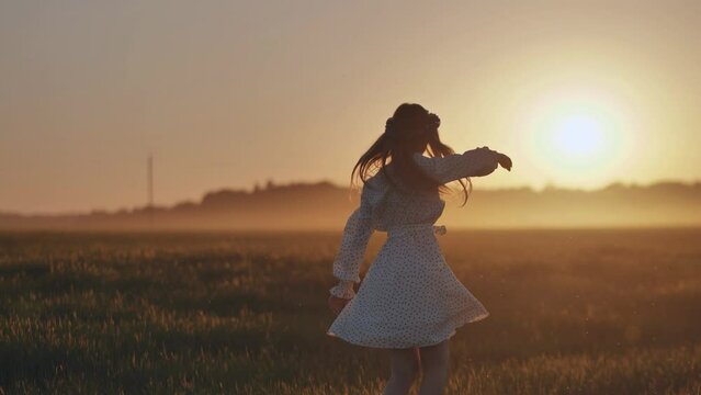 A silhouette of a young Ukrainian girl circling at sunset in the summer.