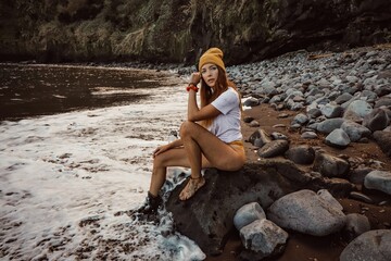 person sitting on the rocks at the beach 