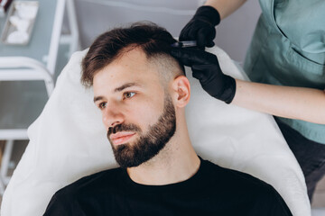 Mesotherapy for man hair. Attractive man receiving injections in his head. Man having mesotherapy...
