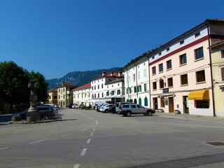 Town center square in Vipava in Littoral region of Slovenia with cars parked in the street and buidling lit by sunlight