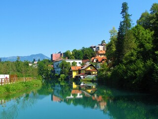 View of peaceful Sava river flowing through the town of Kranj in Gorenjska, Slovenia with a reflection of the houses in the water