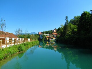 Fototapeta na wymiar View of peaceful Sava river flowing through the town of Kranj in Gorenjska, Slovenia with a reflection of the houses in the water