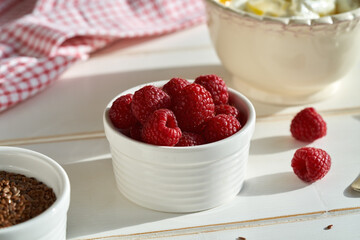 A bowl of raspberries on a white wooden table