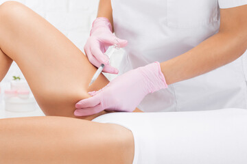 Aesthetic cosmetologist makes lipolytic injections to burn fat on the thighs, hips and body of a woman. Female aesthetic cosmetology in a beauty salon.Cosmetology concept.