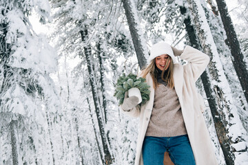 beautiful girl in winter forest with little Christmas tree
