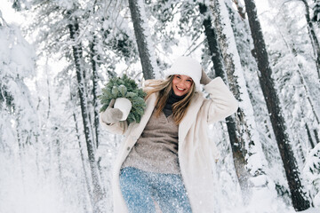 beautiful girl in winter forest with little Christmas tree
