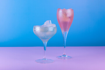 Cocktail glasses with colorful drink on blue and pink background. Summer cocktail party background.