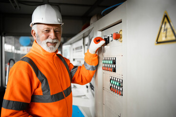 Professional factory worker engineer holding power switch of industrial machines for production or manufacturing.