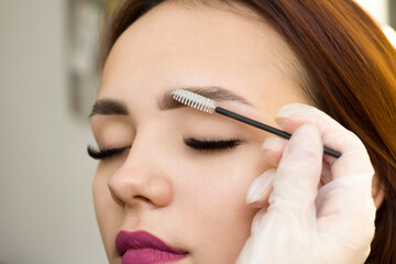 The makeup artist combs his eyebrows with a brush. Eyebrow styling. Permanent makeup. Coloring with henna paint.