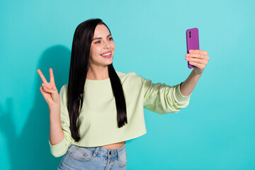 Photo of millennial lady make selfie device show v sign cool symbol isolated over cyan color background