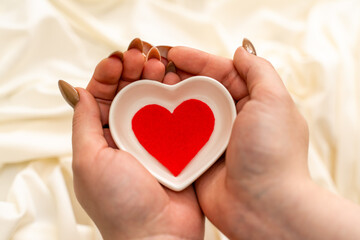 hands hold a red heart on white background