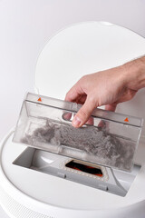 Take out the transparent dust container from the robot vacuum cleaner after cleaning the house. The...