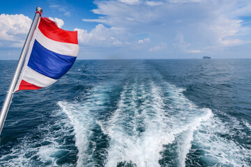 Thai flag with ship trail, stern wake in open sea behind ferry boat in Thailand  