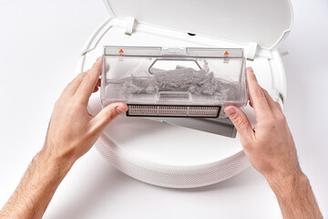 Take out the transparent dust container from the robot vacuum cleaner after cleaning the house. The...