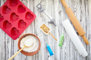 Preparing for baking: heart-shaped silicone mold, rolling pin, confectionery syringe, glaze, flour, sugar. Valentine's day concept. Top view. High quality photo