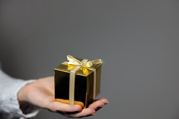 Hands holding gold gift box isolated on gray background. giving present, Birthday,Christmas,Mothersday other Holiday with copy space