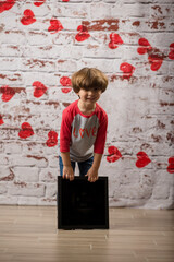 Obraz na płótnie Canvas little Boy holding a blank sign with a heart background black box valentines day 