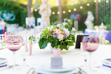 Flower table decorations for holidays and wedding dinner. Table set for holiday, event, party or wedding reception in outdoor restaurant.