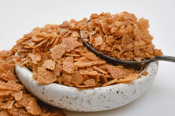 Heap of wafer or waffle crumb in a bowl with spoon on a white background. Selective focus