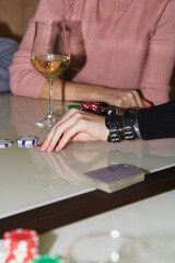 Woman hand make a move with dice in poker game. Cards, dices and glasess of champagne. Candid moment. Poker background lifestyle photography. Enjoying the moment, digital detox with friends