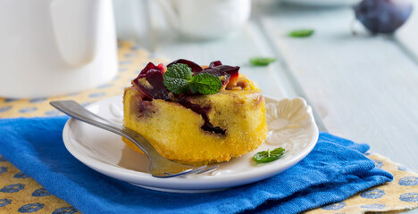 Homemade plum clafoutis or pudding on white ceramic plate. Rustic homemade plum bakery products Selective focus.