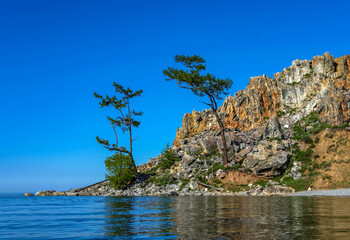Fototapeta na wymiar View of steep shore lake Baikal at the sunny day. Blue sky and water.