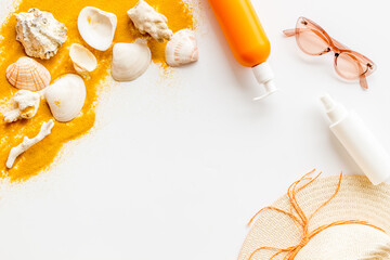 Beach sand and seashells with straw hat and bottles od sunscreen