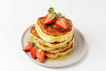 A stack of pancakes with honey and fresh strawberries in plate on white background. Delicious healthy dessert for breakfast.