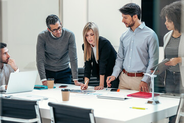 Successful business team standing around computer for presentation of work in a modern startup.