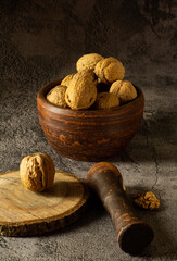 Walnuts on a dark vintage background, walnuts in a clay bowl. Chopped walnuts