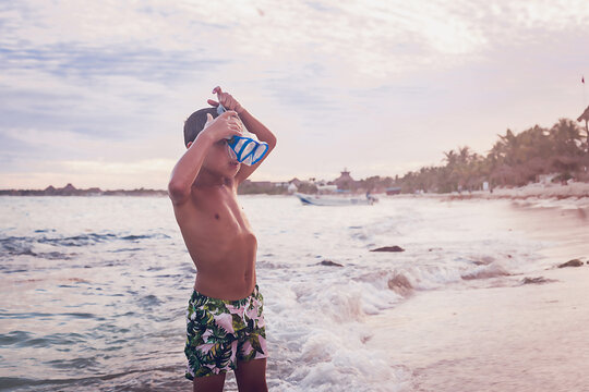 Boy putting on goggles on himself at the beach.