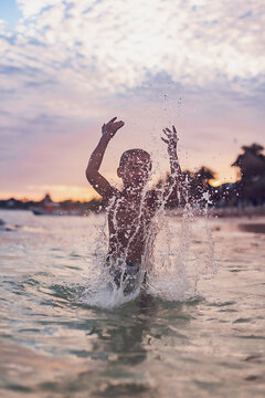Boy splashing water at the beach.