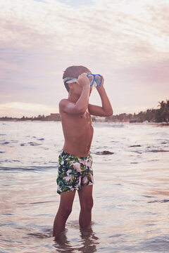 Boy putting on goggles on himself at the beach.