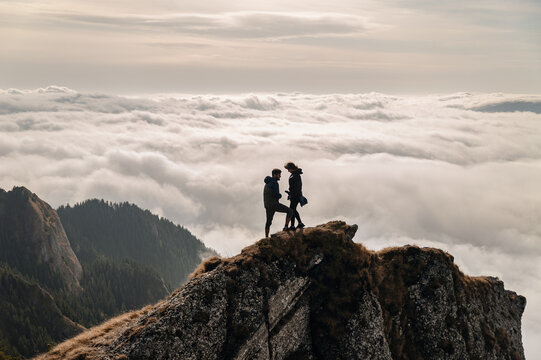 Young Couple enjoying the view above clouds on the mountain
