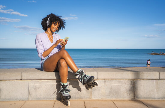 Young woman listening to music on the beach wearing headphones