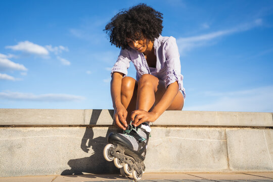 Beautiful young black woman putting on inline skates