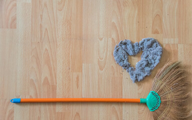 A broom and heart shaped dust on the wooden floor at the living room. Lover and romantic in cleaning day.