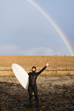 Young female surfer and rainbow before surfing waves is Coastal Oregon