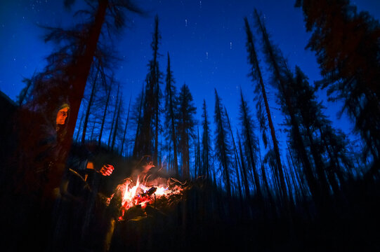 Female staying warm next to a campfire at night