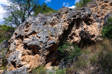 Brown-orange textured rock surface, rock fragment. Summer day.