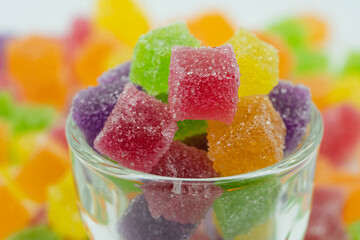 Colorful sweeties gummy candy. Cube candy in glass container. Cute background.