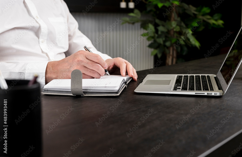 Poster man hands taking notes in planner. businessman sitting at table with laptop and studying online or w