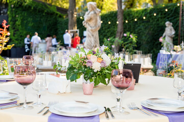Flower table decorations for holidays and wedding dinner. Table set for holiday, event, party or wedding reception in outdoor restaurant.